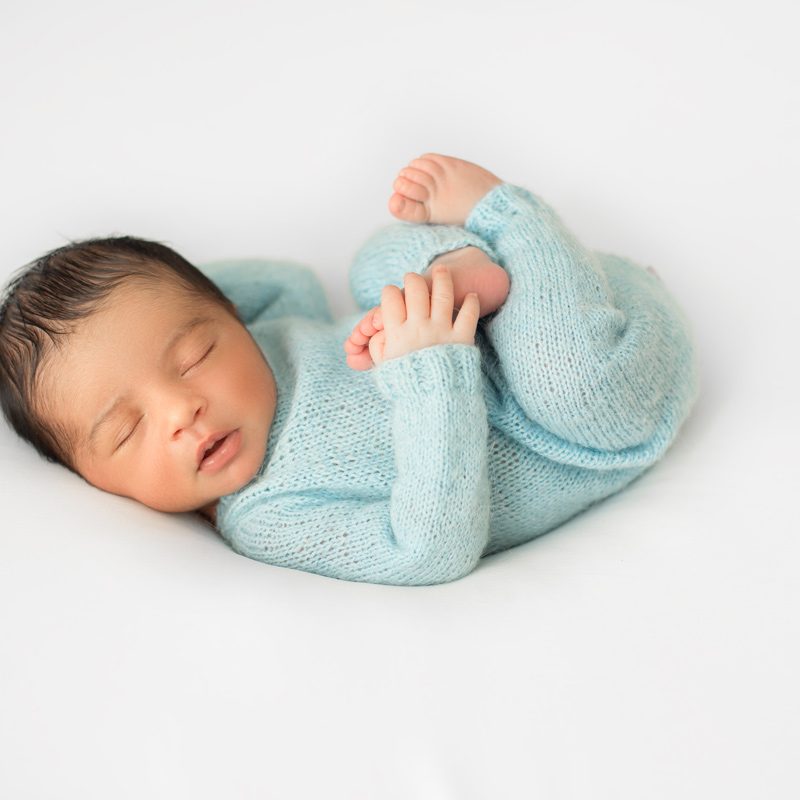 little-infant-newborn-laying-little-white-chair-blue-crocheted-pijamas